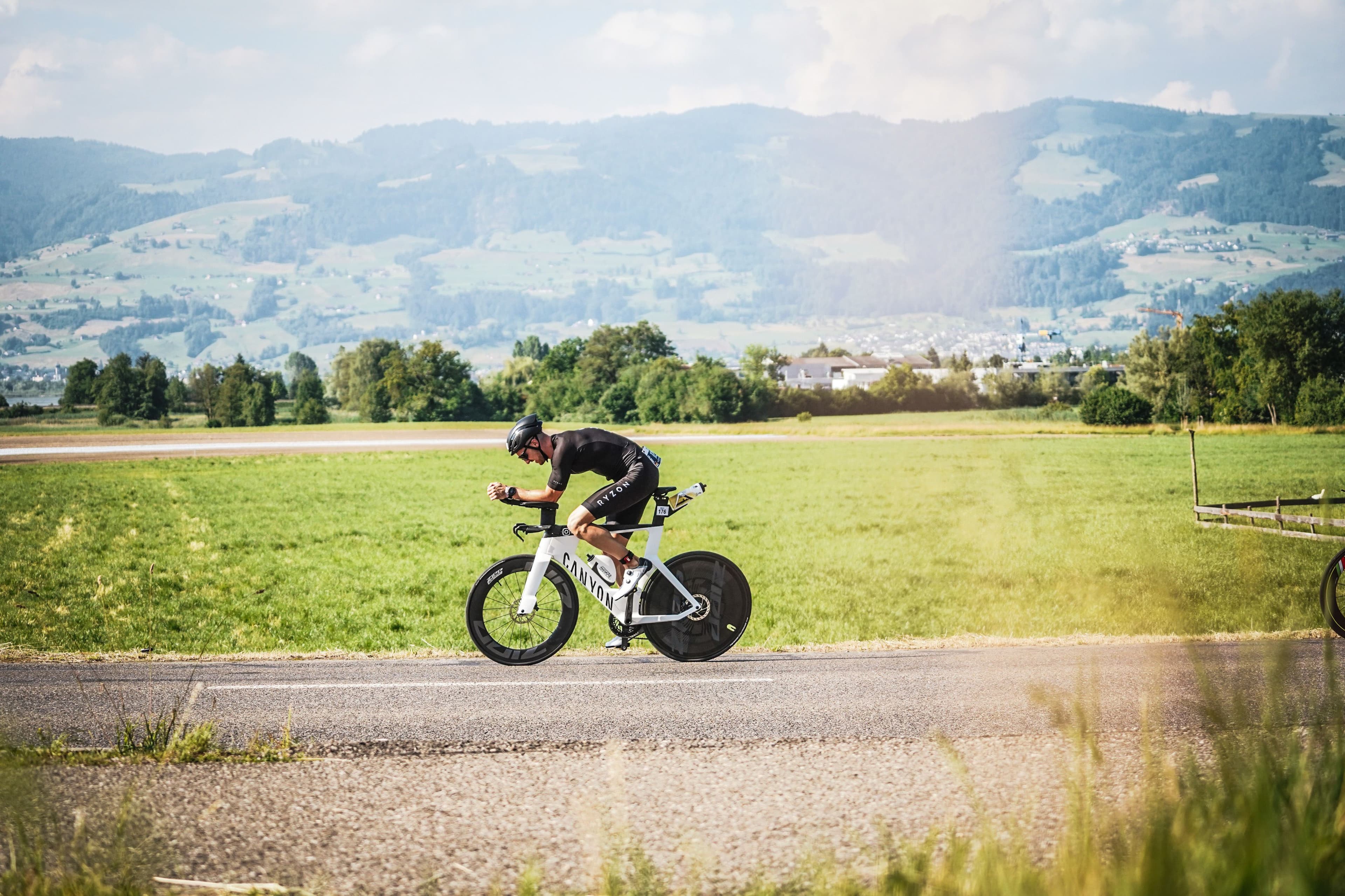 Kevin cycling on a TT bike through Alpine scenery